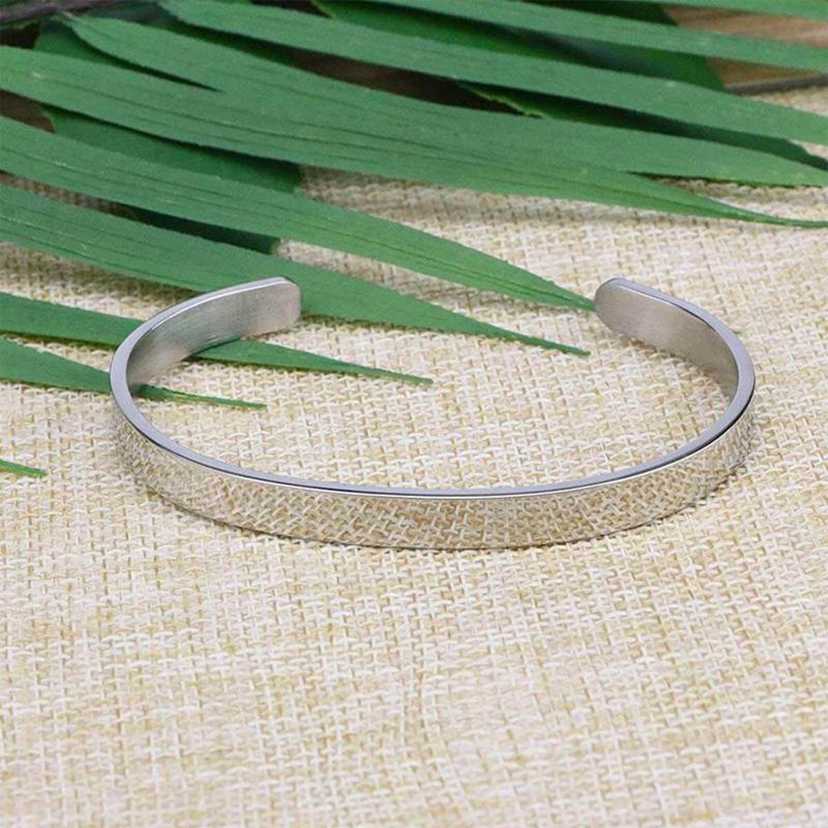 Outer view of the I may not have given you the gift of life but life gave me the gift of you bracelet with silver plating laying flat on a burlap surface with a leafy background